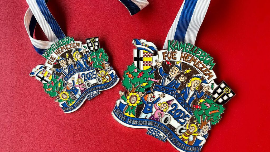 Karnevalsorden 2025 mit buntem Design, blau-weißer Band auf rotem Hintergrund. Thema: Kamellebom füe Hemezem.